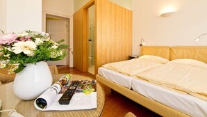 Een slaapkamer met een bed, een houten deur en een bloemenvaas op een tafel.