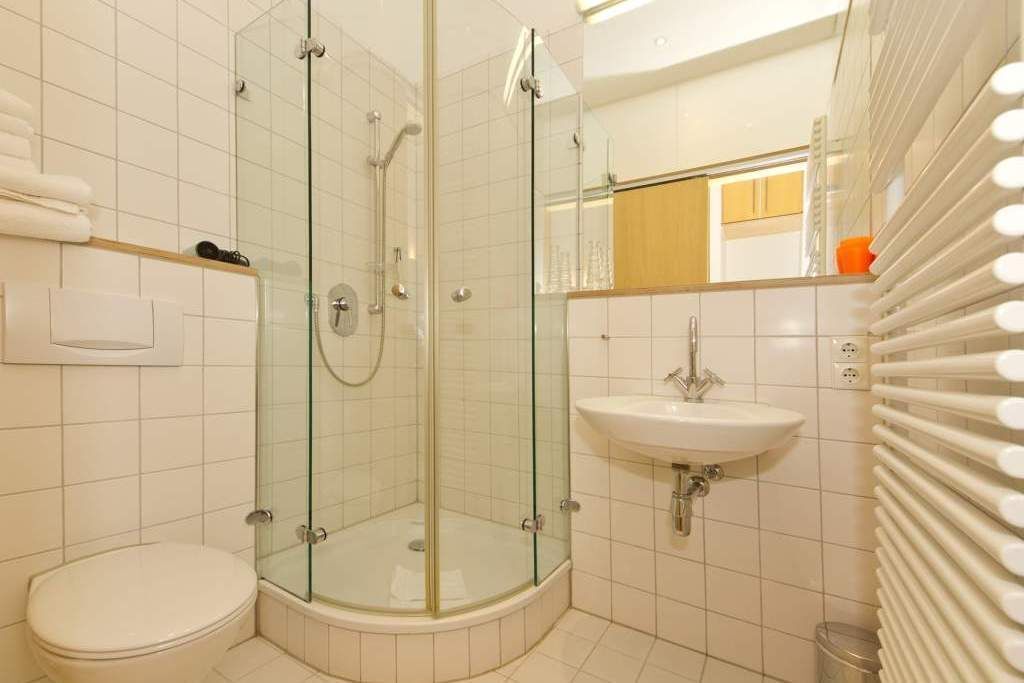 A modern bathroom with a glass-enclosed shower, a white sink, and a toilet.