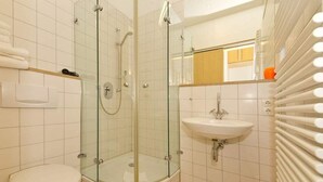 Een moderne badkamer met een douchecabine van glas, een wit wastafelmeubel en een toilet.