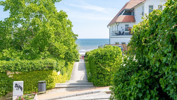 A coastal pathway leading to a building with a red roof, surrounded by lush greenery and overlooking the sea. - Rolandseck, App. 3, Germany (Heringsdorf)