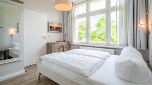 A bedroom with a large window, a bed, a dresser, and a mirror. - Rolandseck, App. 3, Germany (Heringsdorf)