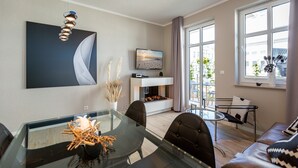 A modern living room with a glass dining table, leather sofa, and a fireplace. - Quartier Frohsinn, app. 04b (Heringsdorf)