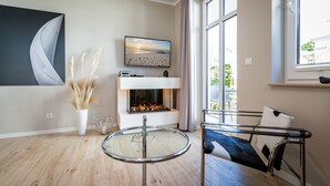 A modern living room with a fireplace, a round glass table, and a comfortable sofa. - Quartier Frohsinn, app. 04b (Heringsdorf)
