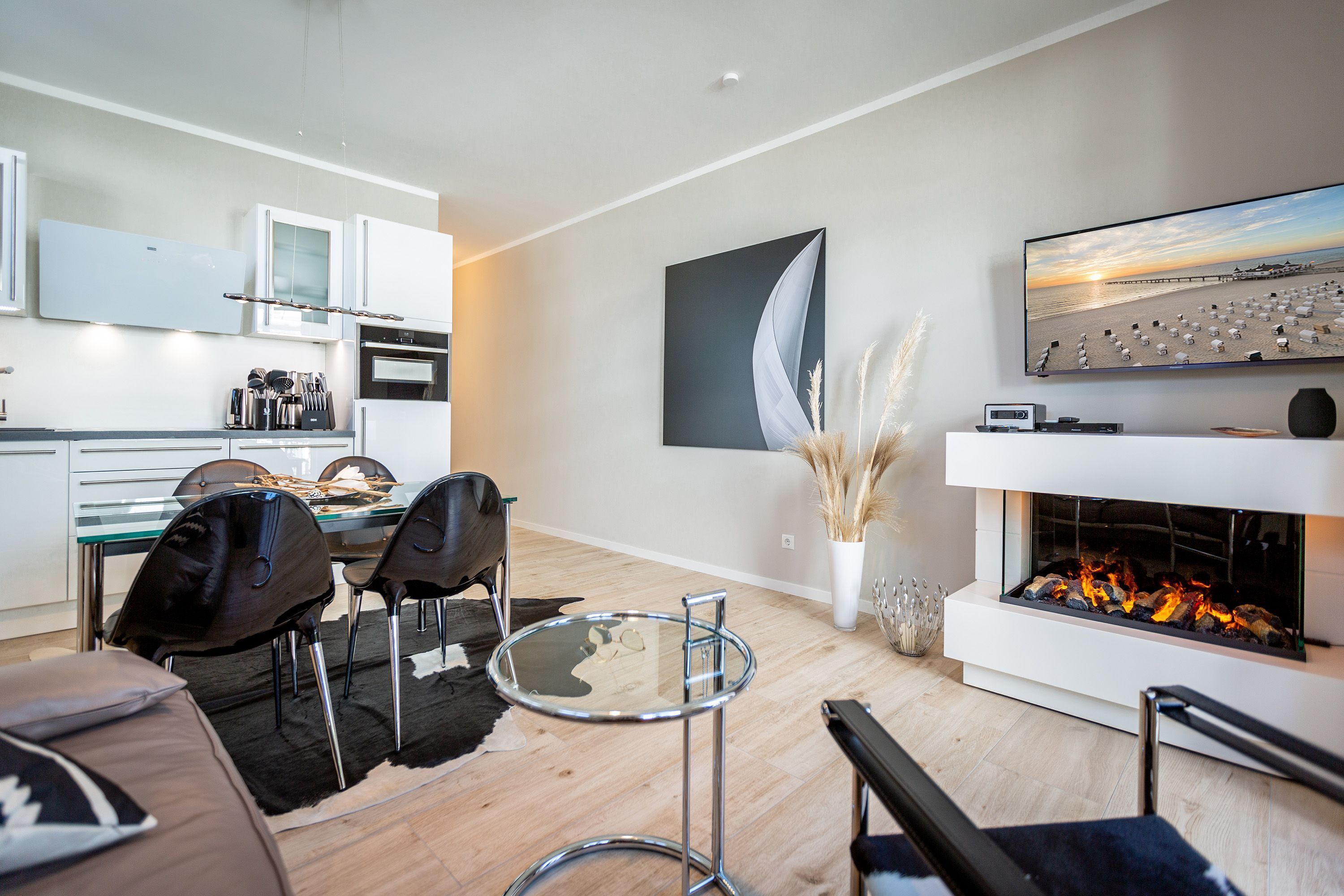A modern living room with a fireplace, a dining area, and a kitchen.