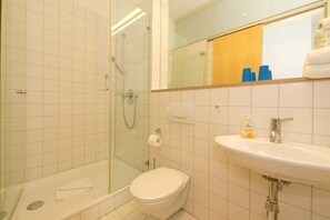 Un baño con ducha, inodoro, lavamanos y espejo.