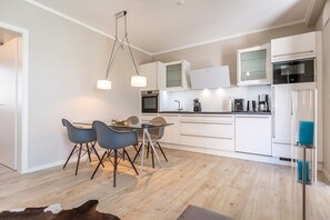 Uma cozinha moderna com armários brancos, uma área de refeições com duas cadeiras e um lustre.