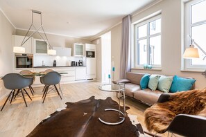 Uma sala de estar moderna com uma mesa de centro de vidro, um sofá com almofadas decorativas, um sofá de couro e um tapete de couro de vaca.