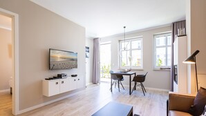 Un saló modern amb un sofà, una taula de centre i una zona de menjador amb cadires i una taula.
