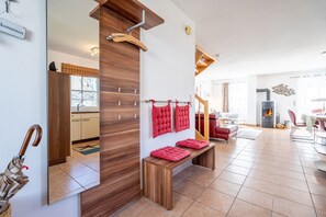 Ein modernes Wohnzimmer mit einer hölzernen Bank, roten Kissen, einem Kamin und einem Essbereich.