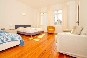 Quarto de hotel com cama, sofá, cadeira e janela.