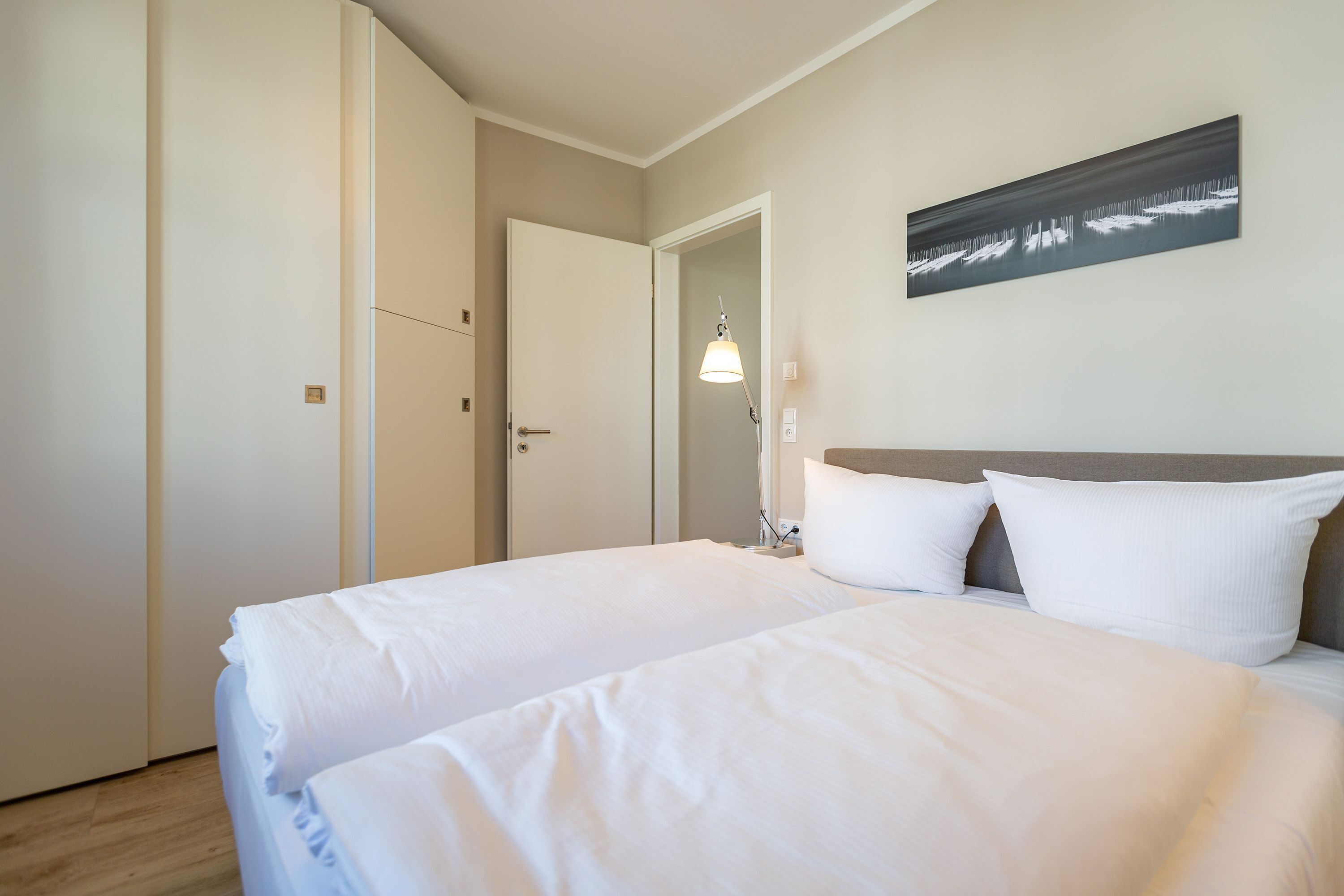 A hotel room with a large bed, a bedside lamp, and a painting on the wall.