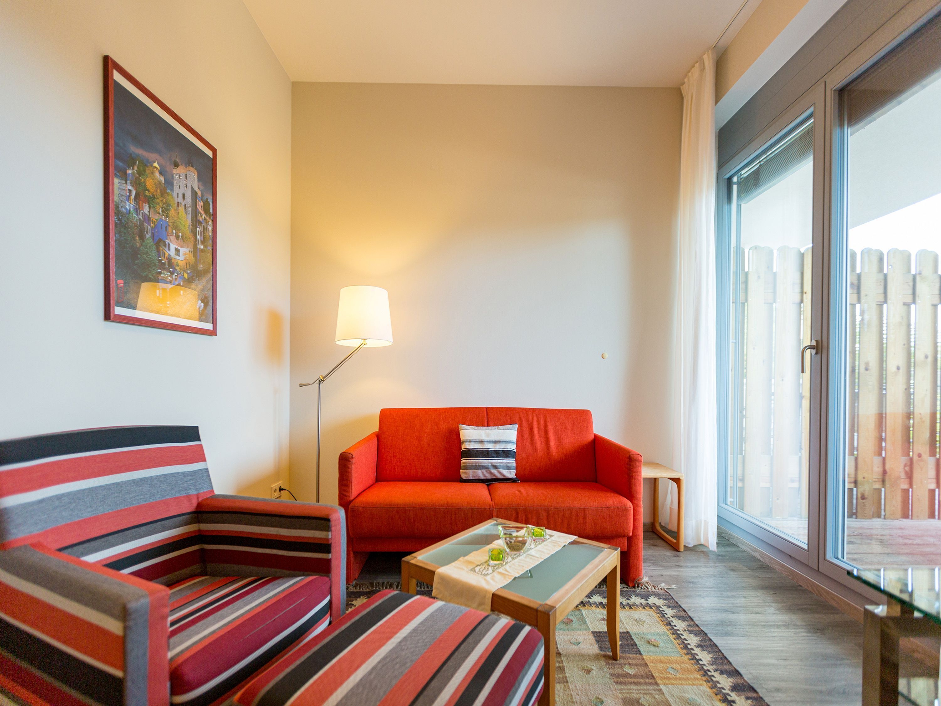 A living room with a striped sofa, a red sofa, and a small table with a tray.