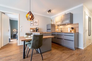 Una cocina moderna con una isla de madera, armarios grises y una lámpara colgante.
