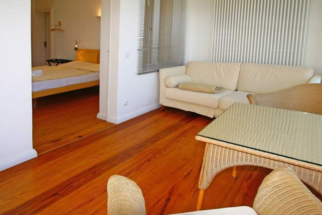 A room with a bed, a sofa, and a glass-top table.