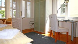 Un dormitorio con una cama, un escritorio, una silla, una lámpara y un ventanal corredizo.