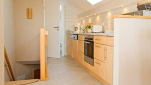 A modern kitchen with wooden cabinets, a built-in oven, and a skylight. - Villa Strandperle, App. 32a (Heringsdorf)