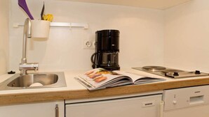 Una kitchenette con un lavamanos de acero inoxidable, una cafetera y un electrodoméstico de la marca Siemens.
