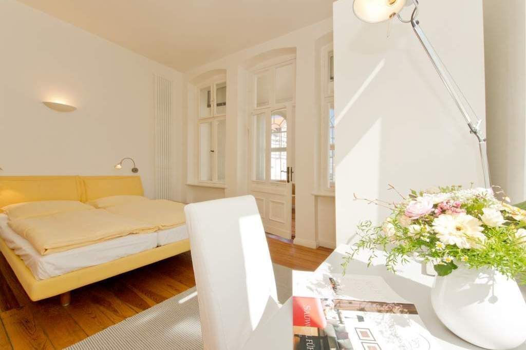 A bedroom with a bed, a desk with a lamp, and a window with curtains.