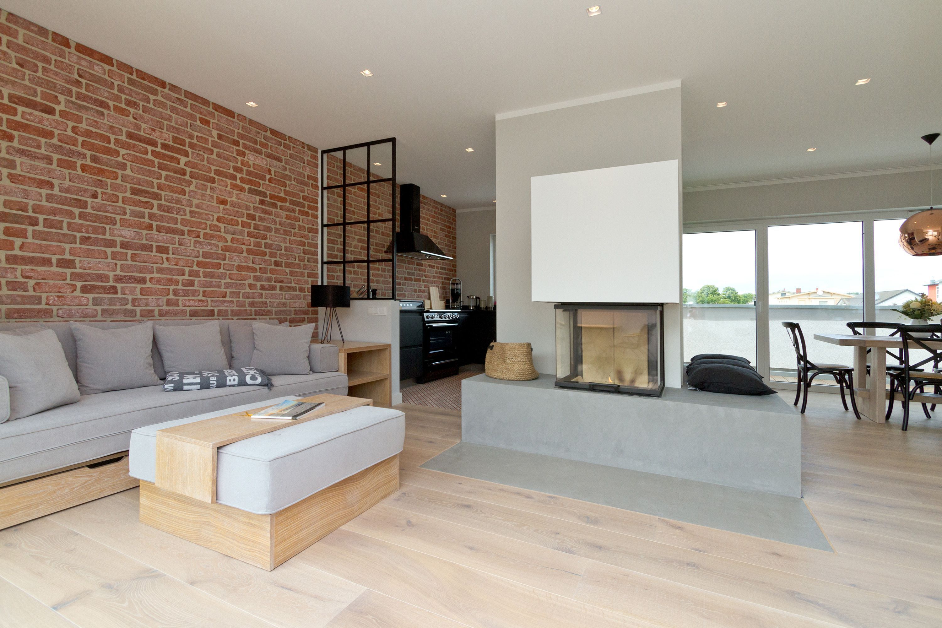 Una sala moderna con pared de ladrillo, chimenea, sofá, mesa de centro y comedor con sillas y mesa.