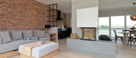 Una sala moderna con pared de ladrillo, chimenea, sofá, mesa de centro y comedor con sillas y mesa.