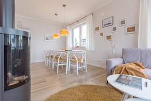 A modern living room with a fireplace, dining area, and a cozy seating space. - Quartier Arinja, App. 01 (Heringsdorf)