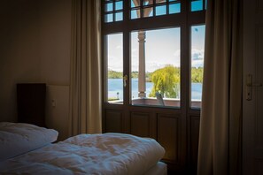 A bedroom with a large window overlooking a lake and greenery. - Villa Strandklause, App. 3 (Heringsdorf)