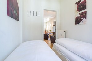 Quarto com duas camas, porta para uma área de refeições e obras de arte nas paredes.