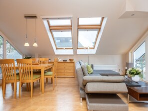 Un espacio habitable moderno estilo loft con comedor, sofá y tragaluces.