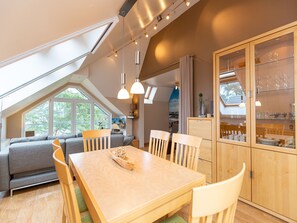 Una cocina moderna con comedor, que incluye una mesa de madera, sillas y un armario empotrado con puertas de cristal.