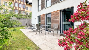 Ein modernes Gebäude mit einer Terrasse, Gartenmöbeln und einem Garten.