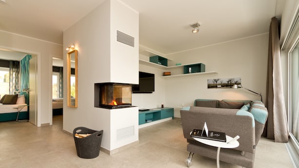 Ein modernes Wohnzimmer mit Kamin, einer Couch, einem Fernseher und einem kleinen Tisch mit einem Buch.
