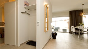 Ein modernes Hotelzimmer mit Dusche, einer Essecke mit Tisch und Stühlen, einem großen Spiegel und Blick ins Freie.