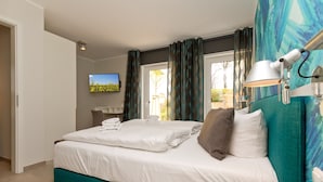 Ein modernes Hotelzimmer mit einem großen Bett, einem Fernseher und Blick ins Freie.