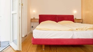 Une chambre à coucher avec un cadre de lit rouge, du linge de lit blanc et deux lampes de chevet.