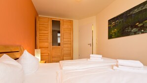 A hotel room with a bed, a wooden wardrobe, and a painting on the wall. - Quartier 47, App. 05 (Heringsdorf)