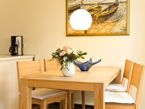 Uma mesa de jantar de madeira com um vaso de flores e um objeto decorativo azul.