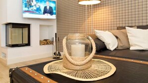Olohuoneessa on lasinen kynttilänjalka pöydällä, seinälle asennettu televisio ja ruutukuviollinen seinä.
