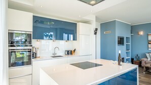 Una cucina moderna con mobili bianchi e blu, un'isola centrale ed elettrodomestici integrati.