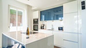 Una cucina moderna con mobili bianchi, una grande isola e vista sull'esterno.