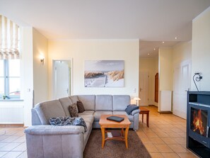 A living room with a grey sectional sofa, a wooden coffee table, a fireplace, and a beach-themed wall art.