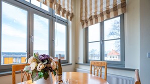 Une table à manger avec des chaises, un vase rempli de fleurs et des verres à vin.