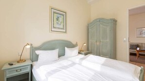 Une chambre à coucher avec un lit, des tables de chevet, une armoire et un tableau encadré au mur.