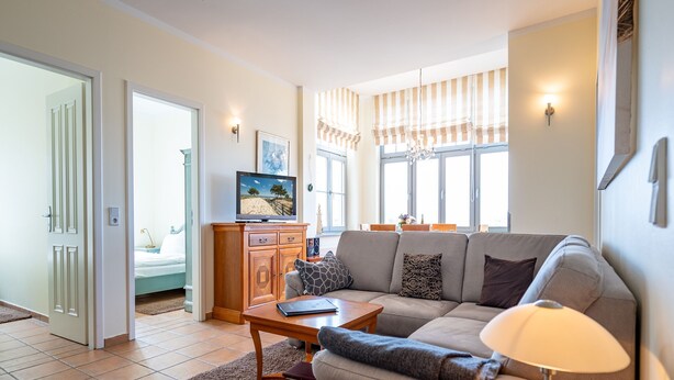 Un salon avec un canapé, une table basse, un téléviseur et une lampe.