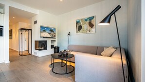 A modern living room with a sofa, a round coffee table, a fireplace, and artwork on the walls.