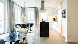 A modern kitchen with a dining area, large windows, and a central island.
