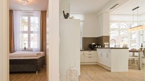 A modern hotel room with a bed, a kitchen area, and a dining table. - Villa Waldschloss, app. 06 (Heringsdorf)