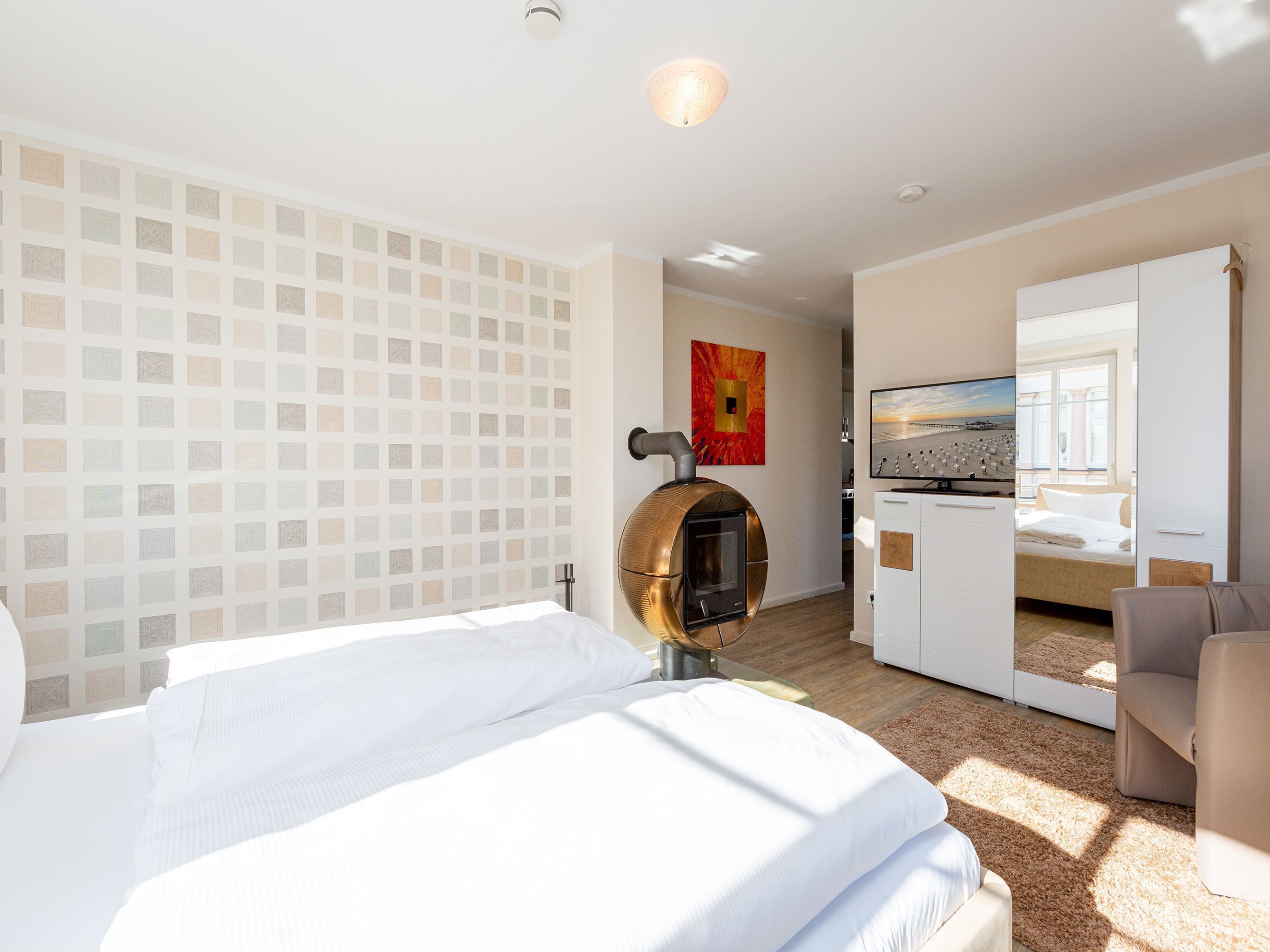 Een hotelkamer met een bed, een open haard, een televisie en uitzicht op het strand.