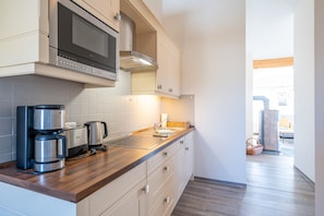 Una cocina moderna con electrodomésticos de acero inoxidable, encimeras de madera y muebles de cocina blancos.