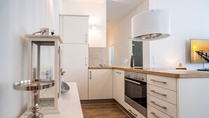 A modern kitchen with white cabinets, a stainless steel oven, and a wooden countertop. - Villa Waldschloss, app. 01 (Heringsdorf)