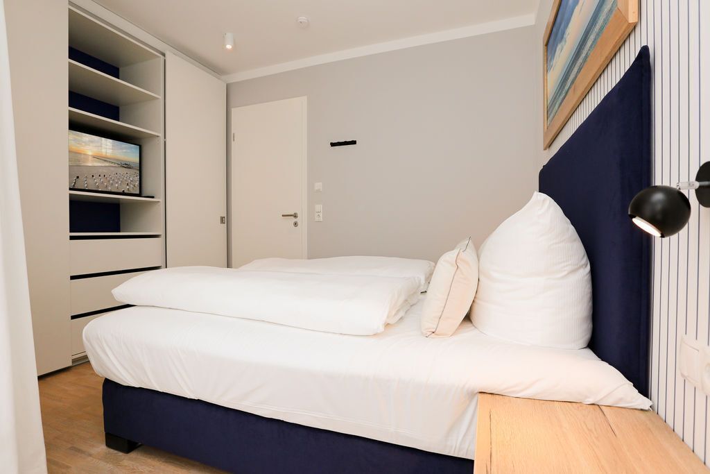 Quarto com cama, guarda-roupa, porta e luminária na parede.